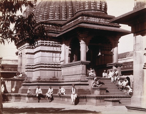 Indian men sitting on steps outside a domed building in Bombay during an outbreak of plague. Photograph, 1896/1897.