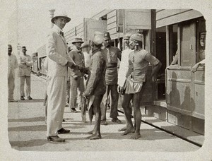 view Medical officers watching the arrival of a train at Sion railway station, during the epidemic of plague in Bombay. Photograph attributed to Captain C. Moss, 1897.