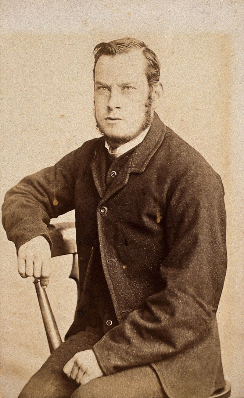 A young man, seated, with an intense expression in his eyes. Photograph by J. Davis., by John Davis