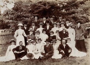 view A group of hospital staff, including nurses wearing matching straw hats, standing outdoors. Photograph.