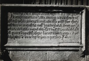 view Hospital de la Santa Cruz, Barcelona: a stone inscription above the water fountain in the courtyard. Photograph.