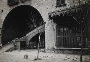 view Hospital de la Santa Cruz, Barcelona: a staircase leading up to the women's department; to the right is the metal barred window of the pharmacy. Photograph.