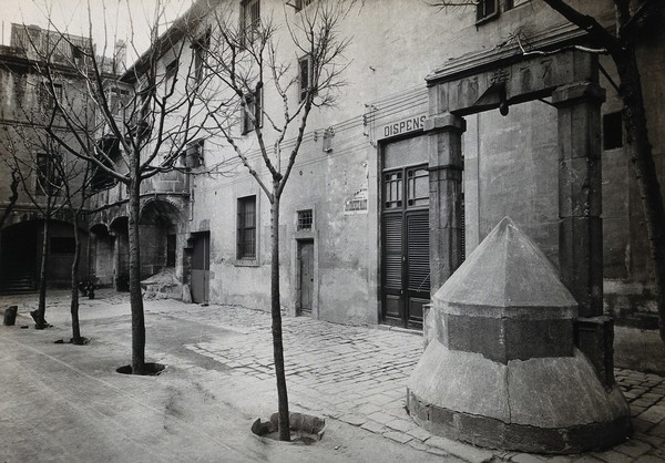 Hospital de la Santa Cruz, Barcelona: a long view of the courtyard; to the right can be seen the stone well and the door to the dispensary. Photograph.