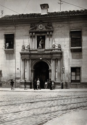 view Hospital San Juan de Diós, Granada: gateway of the hospital showing the stone figure of the founder above. Photograph, ca.1900.