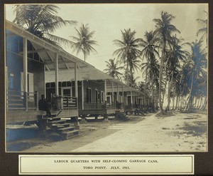 view Panama Canal workers' quarters (West Indian and Panaman) surrounded by palm trees: wooden cottages provided with self-closing dustbins; West Indian resident in foreground. Photograph, 1911.