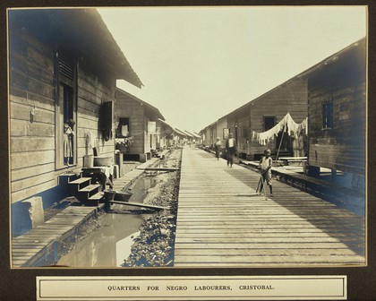 Panama Canal workers' (West Indian and Panaman) quarters: exterior view of wooden huts with resident children in foreground. Photograph, ca. 1910.