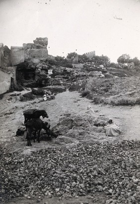 Fez, Morocco: the path to Bab Ghissa with ruins in the background and donkeys and cloaked figures in the foreground. Photograph, 1922.