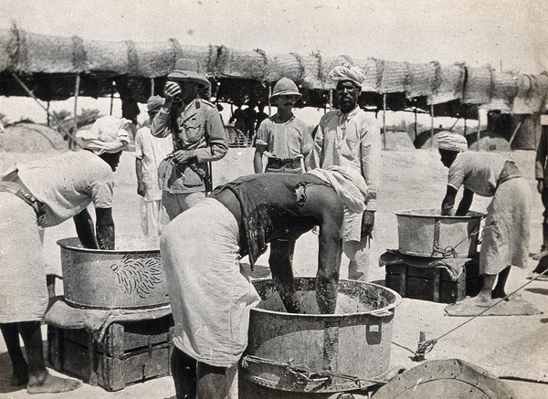 Bakery at the Indian army base in Makina, Basra, Iraq (formerly Mesopotamia): British soldiers watch the preparation of the dough by Sikh (?) bakers. Photograph, 1914/1918 (?).