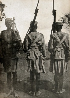 Tanzania (?): three soldiers of the King's African Rifles (KAR), displaying new uniforms. Photograph, 1914/1918 (?).