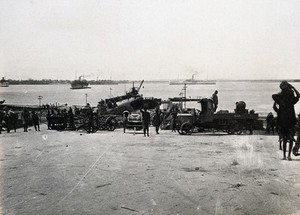 view Kilwa Kisiwani, Tanzania: wharves with vehicles, soldiers and Tanzanians; boats in the background. Photograph, 1914/1918.