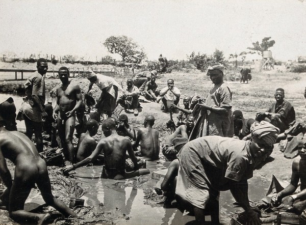 Mpara Hill (?), Tanzania: Tanzanian men (railway porters) washing their clothes in a muddy stream. Photograph, 1914/1918 (?).