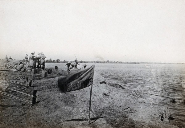 The junction of the Euphrates river and the Shatt al Arab river, Iraq: (British ?) soldiers on the river bank. Photograph, 1914/1918.