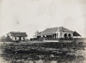 view Cartagena, Colombia: a large stone building used for the market, next to a wooden house. Photograph, 1910/1920 (?).