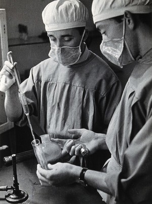 view Yellow fever: two scientists wearing face masks at work in a laboratory. Photograph, 1910/1930 (?).