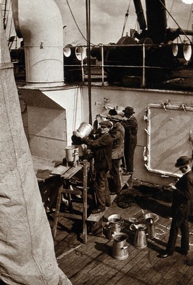 Ship fumigation using hydrogen cyanide: operators at work with metal funnels on board the ship. Photograph by P. G. Stock, 1900/1920.