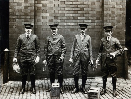 Liverpool Port Sanitary Authority rat-catchers dressed in protective clothing with traps and equipment, Liverpool, England. Photograph, 1900/1920.