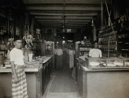 Kuala Lumpur, Malaysia: a food shop with Malay staff, showing open sacks and boxes of produce, in an urban area prone to outbreaks of typhus. Photograph, 1915/1925.