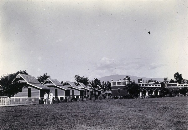 Chiengmai Leper Asylum, Thailand: a row of wooden cottages and dormitory building. Photograph, 1921.