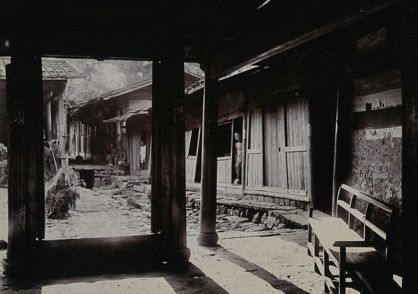 Leper asylum, Foochow (Fuzhou), China: patients seated outside basic shelters. Photograph, 1880/1910.