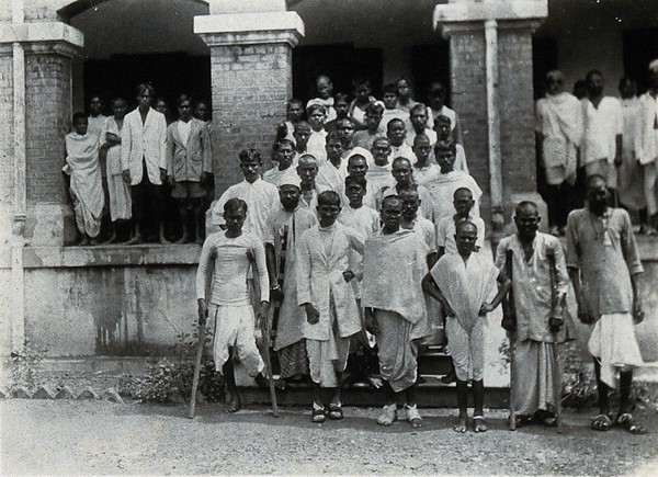 The Albert Victor asylum for lepers, Gohea, Calcutta, India: male patients in white robes on the steps of the male block. Photograph, 1900/1920.