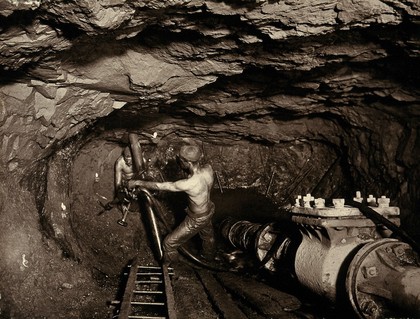 Tincroft tin mine, near Camborne, Cornwall: two miners at work in a mine shaft. Photograph by J. C. Burrow, 1890/1910.