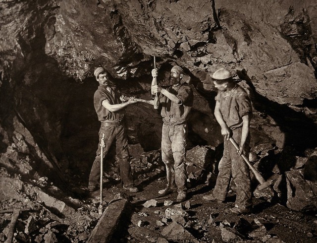 A tin mine, Camborne, Cornwall: three miners at work in a mine shaft ...