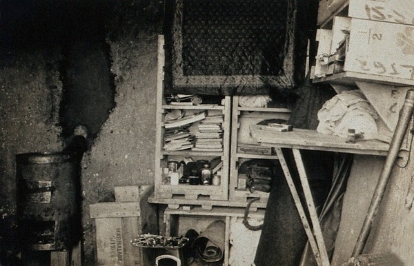 World War One: a dug-out interior showing shelving and stove. Photograph, 1914/1918.