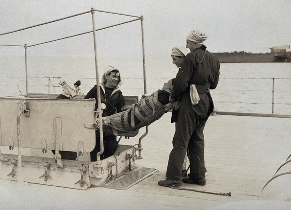 World War One: an injured man on a stretcher being taken below deck aboard a hospital ship. Photograph, 1914/1918.