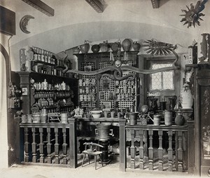 view The pharmacy of C. Hersbrunnen (?), Lucerne, Switzerland: a reconstruction of the 18th century shop showing pharmacy equipment and decorations: front view. Photograph, ca. 1920.