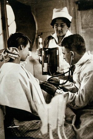 view The National Hospital for Diseases of the Heart, London: a doctor and nurse use an electro-cardiograph to give a patient a heart test. Photograph, ca. 1922.