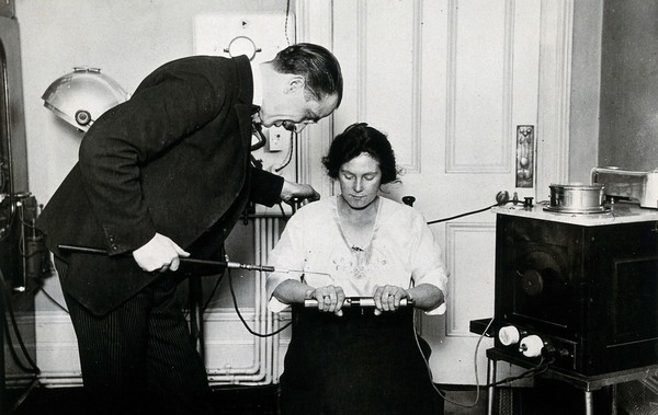 The Electrical Vacuum Tube: W.D. Ross demonstrates its medical use with a woman patient. Photograph, ca. 1922.