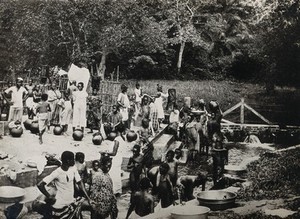 view Old Calabar, Nigeria: local people gathering drinking water from a river, filling vessels and washing clothes (?). Photograph, 1910/1920.