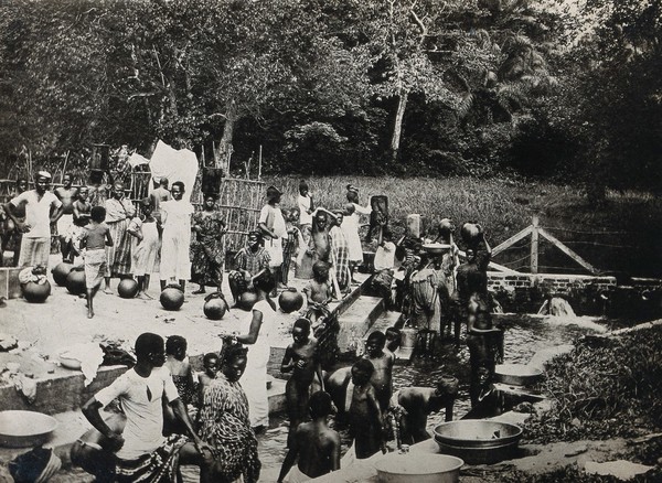 Old Calabar, Nigeria: local people gathering drinking water from a river, filling vessels and washing clothes (?). Photograph, 1910/1920.