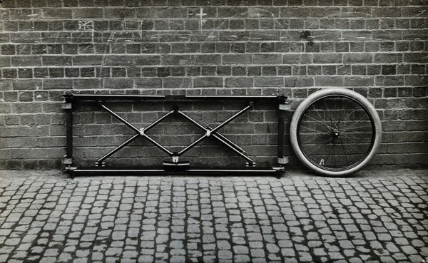 Closes' mono-wheel stretcher, in closed position, folded against a wall. Photograph, 1915/1918.