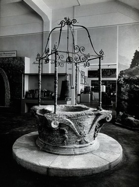 Stone wellhead, possibly Italian, with a bucket, winch and metal framework attached, dating from the fourteenth or fifteenth century (?), shown on display in the Deutsches Museum, Munich. Photograph, ca. 1936.