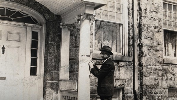 A health officer attaching a mumps quarantine sign to the front porch of a house in Pennsylvania. Photograph, 1920/1935?.