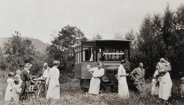 A mobile health unit, parked in a Pennsylvania field: patients are shown awaiting treatment by the unit's health practitioners. Photograph, 1920/1930?.