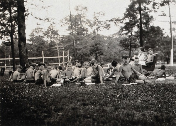 Children having outdoor lessons at the Cresson Sanatorium for tuberculosis, Pennsylvania: the children are all stripped to the waist and are seated on the grass. Photograph, 1920/1940?.
