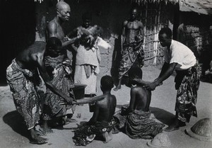 view Benin: a healing ceremony during which patients are swept with brooms after their illness has been driven into some chickens. Photograph by H.V. Meyerowitz, 19--.