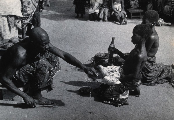 Benin: a healing ceremony during which patients prepare for their illness to be driven into the chickens they are holding, who will then be sacrificed to the god Legba. Photograph by H.V. Meyerowitz, 19--.