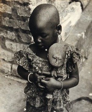 view Ghana: a child holding an Akuaba doll. Photograph by H.V. Meyerowitz, 19--.