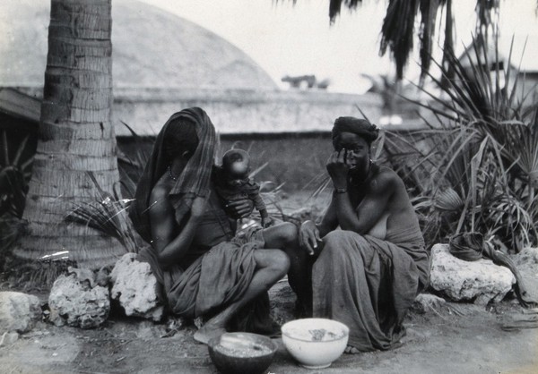 Massawa, Eritrea: two Somali women eating outside; one covers her face to ward off the 'evil eye'. Photograph (by Kurt Lubinski?), 1940/1960.