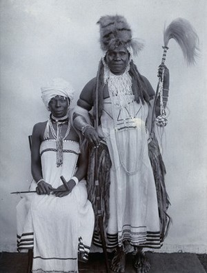 view Africa: a man (a witchdoctor?) and a woman in ceremonial dress. Photograph, 1920/1930.