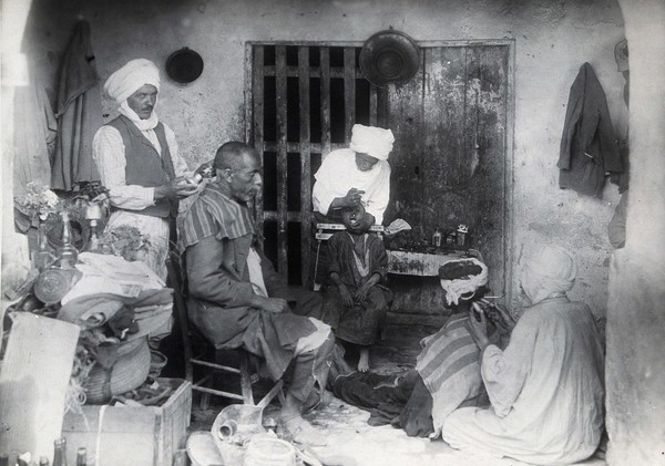 Sudan: barbering, tooth-drawing and cupping being practised. Photograph, ca. 1920.