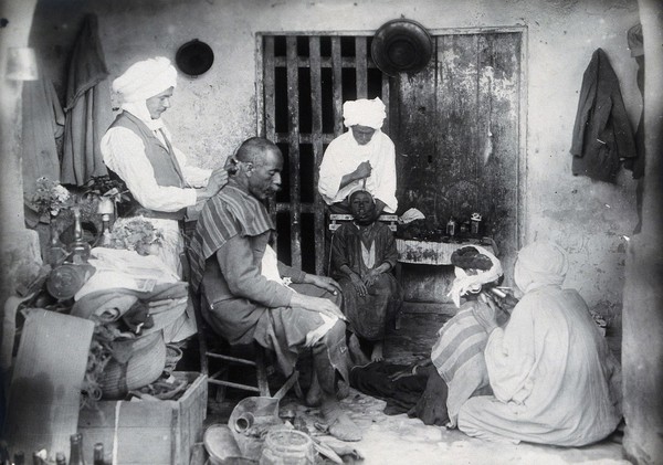 Sudan: barbering, tooth-drawing and cupping being practised. Photograph, ca. 1920.