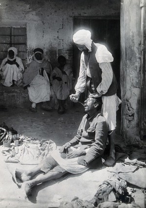 view Sudan: an operator extracting a tooth of a man seated in the street. Photograph, ca. 1920.