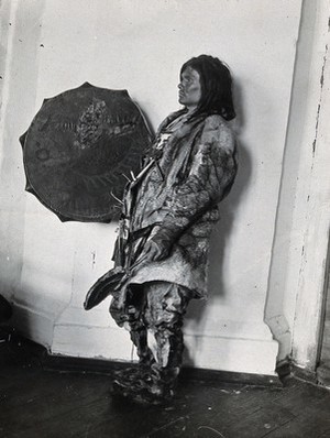 view Siberia: an Ostiak medicine man wearing animal skins and with a shield: studio portrait: side view. Photograph, ca. 1920 (?) of a photograph by Marya Czaplicka, 1914/1915.