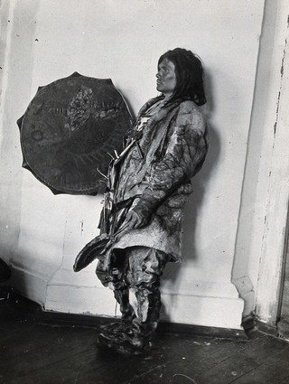Siberia: an Ostiak medicine man wearing animal skins and with a shield: studio portrait: side view. Photograph, ca. 1920 (?) of a photograph by Marya Czaplicka, 1914/1915.