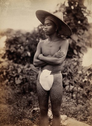 view Myanmar (Burma): a young man with elaborate tattoos on his waist and thighs. Photograph.