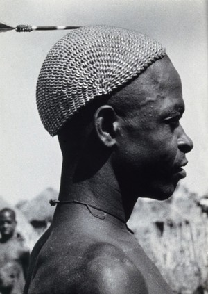 view British Togoland or Ghana: a man with metal woven into his hair. Photograph by Kurt Lubinski, 19--.